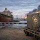 Bitcoin container halted at a port checkpoint as smoke rises in the distance, reflecting how escalating Iran war fears are weighing on the crypto market